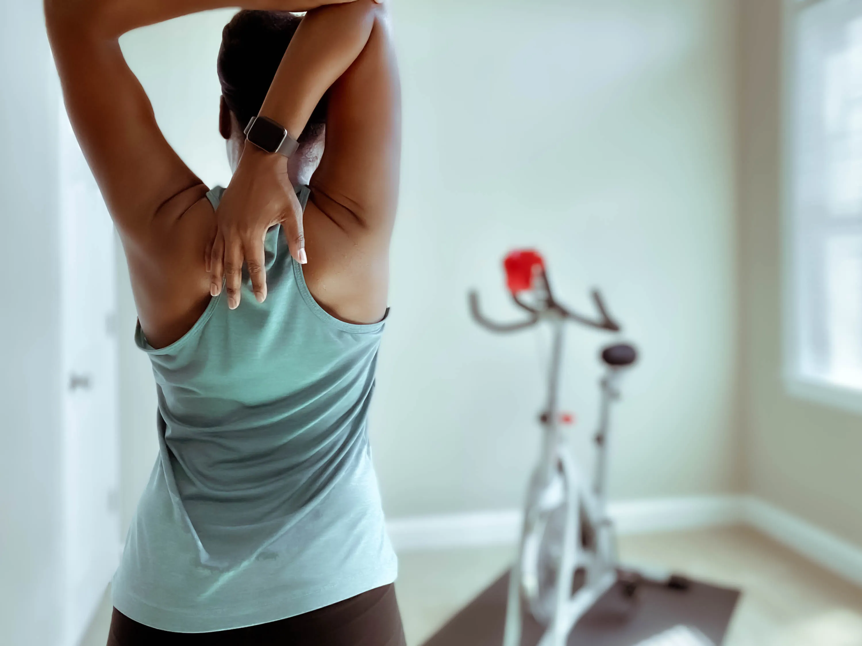Woman stretching right arm to reach down her back